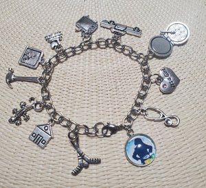 A MATILDA Bookworm charm bracelet featuring silver metal and a variety of charms. A MATILDA Bookworm charm bracelet featuring silver metal and a variety of charms.