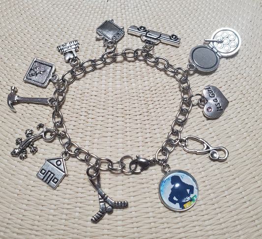 A MATILDA Bookworm charm bracelet featuring silver metal and a variety of charms.
