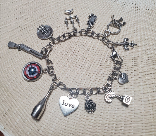 A LES MISERABLES Charm Bracelet from The Lobby Boutique with various charms on it.