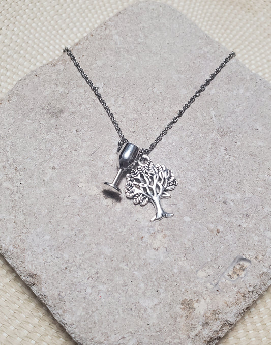 A silver INTO THE WOODS Witch Necklace by The Lobby Boutique featuring a tree and a wine glass.