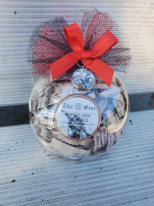 A glass jar filled with money and a red ribbon, perfect as a NEWSIES Christmas Ornament or Christmas ornament for Newsies fans from The Lobby Boutique.
