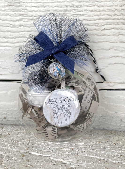A blue and white NEWSIES "Seize the Day" Christmas Ornament with a ribbon, perfect as a stage door gift or Christmas ornament from The Lobby Boutique.